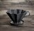 Vista lateral sobre uma mesa do Coador de Café em Cerâmica Preto que usa filtro V60-02 ou filtro de pano
