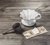 mini coador de café individual em cerâmica-branco-v60-01, colher medidora e filtro de pano sobre uma mesa