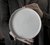 Mãos segurando um prato de sobremesa branco da Felline Cerâmica
