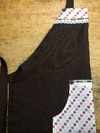 Avental frontal marrom em oxford com estampa de poá em tricoline Bolso canguru no centro Detalhe em bordado inglês e fita 