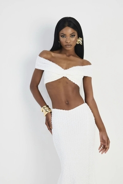 Modelo usando um conjunto de vestido branco, com detalhes em renda 3D, composto por uma blusa off-shoulder e uma saia longa.