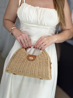 Mulher usando um vestido Lavinia de viscolinho, segurando uma bolsa de palha com detalhes em couro.