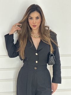 Modelo usando um conjunto de blazer curto e calça de linho, com acessórios elegantes.