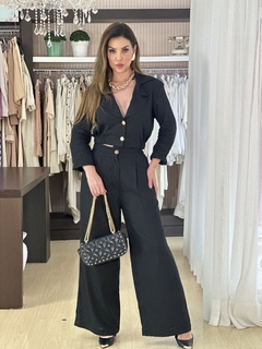 Modelo vestindo o Conjunto Melanie Linho, composto por blazer curto e calça ampla, em ambiente de loja de roupas.