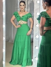 Modelo vestindo um vestido longo verde com babados e detalhes em linho, posando em frente a um espelho iluminado.