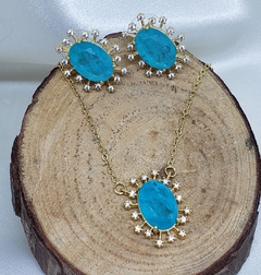 Conjunto dourado com cristal oval azul tiffany e zircônias cristais.