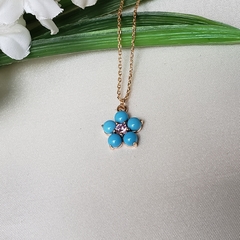 Colar dourado com pingente flor em resina azul claro e zircônia rosa - comprar online