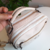 Bolsa baú off white com alça, mostrando detalhes das costuras e zíperes.