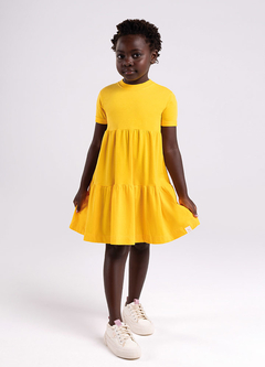 Vestido infantil amarelo de meia malha para meninas, com mangas curtas e saia rodada, usado por uma criança.