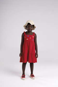 Menina usando um vestido vermelho com detalhes coloridos e um chapéu de crochê.