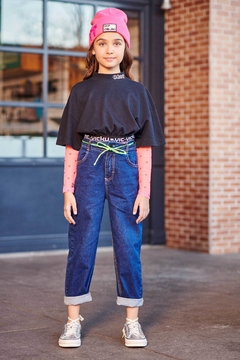 Garota usando calça jeans baggy de cintura alta, camiseta preta e touca rosa, posando em ambiente urbano.