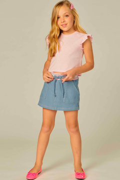 Menina usando shorts saia infantil em malha, com blusa rosa e sapatos rosa.