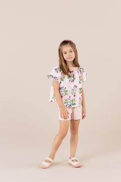 Menina usando conjunto infantil de bata estampada e shorts de tricoline na cor rosa, com estampa floral.