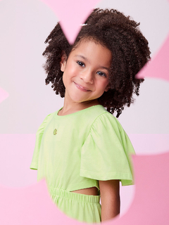 Menina sorridente usando um vestido verde com aberturas laterais e mangas bufantes.