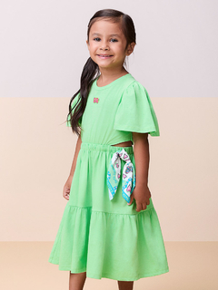 Menina sorrindo usando um vestido verde com lenço estampado na cintura