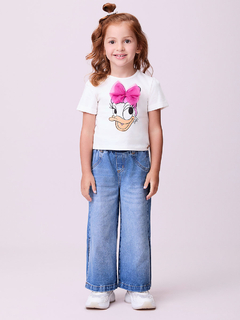 Menina usando blusa branca com estampa da Daisy Duck e laço de tule rosa, combinada com calça jeans larga.