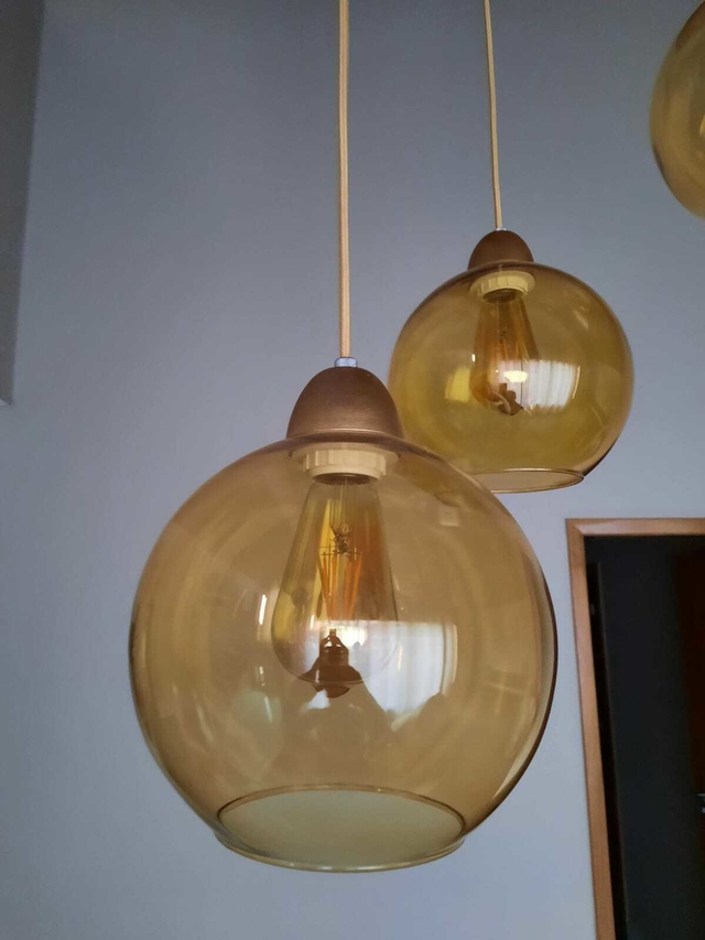Lustre pendente de vidro âmbar com uma lâmpada exposta, pertencente à linha Sarvah.