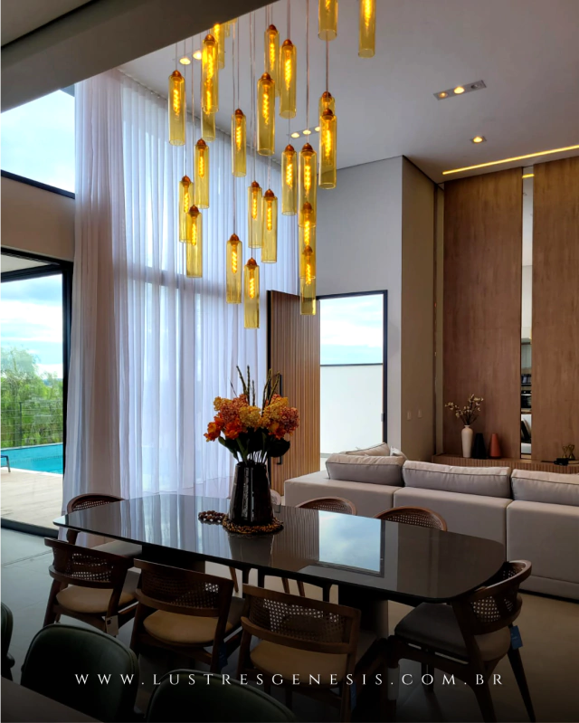 Iluminação pendente da linha Dunáh em vidro âmbar, destacando-se em um ambiente moderno com mobiliário elegante.