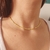 Choker com mini bolinhas douradas, exibido em um pescoço feminino.