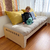 Cama Montessori evolutiva y reversible con carrito, madera multilaminada, con colchón de algodon hecho a mano, suave y almohadón amarillo, ubicada en una habitación con luz natural. Cama evolutiva y reversible. Cama Montessori. Cama con carro para niños