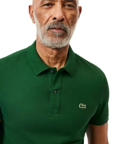 Homem usando uma camiseta polo slim fit piquet verde da Lacoste com logotipo bordado