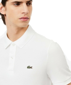 Homem usando uma polo Lacoste slim fit branca com logo bordado no peito.