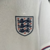 Emblema da camisa da Seleção da Inglaterra I 24/25, mostrando leões e flores em um fundo branco.