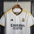 Camisa branca do Real Madrid I 23/24, com detalhes em preto e amarelo, e logo da Adidas.