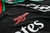 Detalhe da camisa preta do Arsenal II 24/25, mostrando o logo do clube em vermelho.