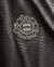 Logotipo bordado do Bayern de Munique em uma camisa preta, destacando detalhes em bege.