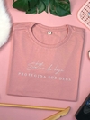 tshirt na cor rosa claro, com detalhe de frase sobre Deus, blusa com frase evangélica e detalhe em alto relevo, blusa feminina gola redonda e manga