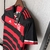 Camisa do Flamengo com listras vermelhas e pretas, pendurada em um cabide.