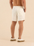 Homem de costas usando shorts de linho curto na cor off white.