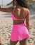 Short Saia fitness na cor rosa com cintura alta, saia evasê e proteção solar. Ideal para beach tennis e academia.