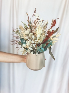 Vaso de cerâmica bege com flores secas em tons de branco, verde e marrom