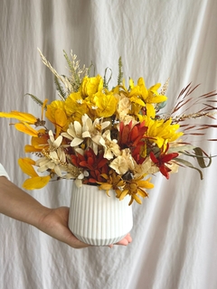 Vaso de cerâmica branco com flores secas em tons de amarelo e laranja