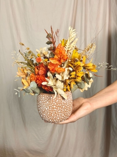 Vaso de cerâmica marrom com flores secas em tons de amarelo e laranja