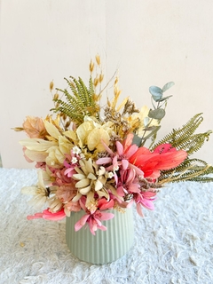 Vaso de cerâmica verde acinzentado com arranjo de flores secas em tons de rosa e branco