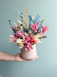 Vaso de cerâmica bege com flores secas em tons de rosa, branco, azul e verde