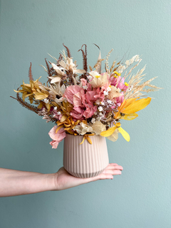 Vaso de cerâmica bege com flores secas em tons de rosa, amarelo, branco e verde