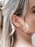 Mulher usando brinco ear cuff liso com banho dourado em ouro 18k.