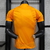 Camiseta de goleiro do Real Madrid na cor laranja, com o logo do time e patrocinador em destaque. camisa-camisas-blusa-blusas-uniforme-real-madrid-ii-2-segunda-segundo-24-25-jogador-adidas-masculina-masculino-laranja-vini-jr-mbappe-bellingham