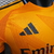 Camiseta de goleiro do Real Madrid na cor laranja, com o logo do time e patrocinador em destaque. camisa-camisas-blusa-blusas-uniforme-real-madrid-ii-2-segunda-segundo-24-25-jogador-adidas-masculina-masculino-laranja-vini-jr-mbappe-bellingham