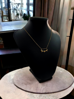 Collar de oro de 18 kilates con diseño de corazones, exhibido en un maniquí negro sobre una base circular.