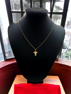 Collar con cruz de oro de 18 kilates, pequeño y arenado, exhibido en un maniquí negro.