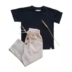 Conjunto infantil de camiseta preta e calça saruel clara, ambos feitos de algodão sustentável.