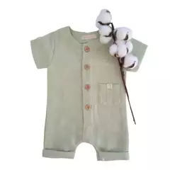 Romper de bebê feita em algodão sustentável, com botões de madeira e bolso frontal, disponível em três cores