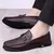 sapatos loafer masculino marrom Alfred com detalhe em metal, usado por homem com calça preta.