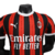 Nova camisa titular do AC Milan 24/25 versão jogador: listras vermelhas e pretas em tom sobre tom, gola e punhos brancos. Escudo e logo PUMA em branco. Costas vermelhas com selo dos 125 anos.