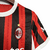 Nova camisa titular do AC Milan 24/25: listras vermelhas e pretas em tom sobre tom, gola e punhos brancos. Escudo e logo PUMA em branco. Costas vermelhas com selo dos 125 anos.